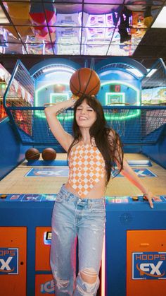 a woman standing in front of a basketball on top of a pinball game machine