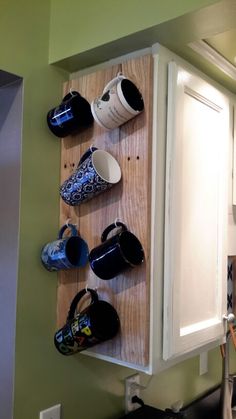 a wooden shelf with cups and mugs mounted to it's sides in a kitchen