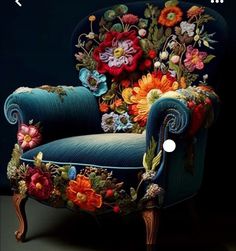 a blue chair with colorful flowers on it's back and arms, sitting in front of a dark background