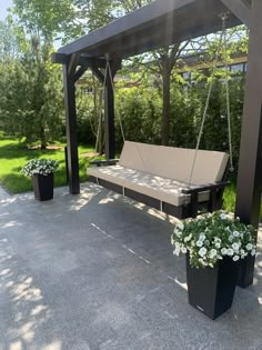 an outdoor swing with two planters on the ground