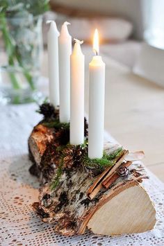 four white candles sitting on top of a piece of wood