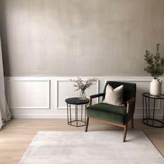 a living room with a chair, table and two vases on the floor next to each other