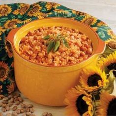 a yellow bowl filled with food next to sunflowers