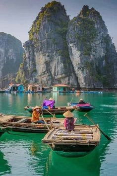 two people on small boats in the water with mountains in the backgrouds