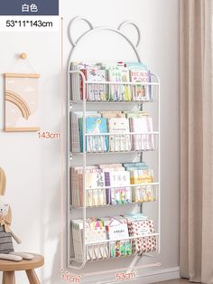 a white rack with books and magazines on it in front of a curtained window