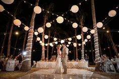 a bride and groom sharing their first dance under paper lanterns