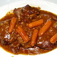 a white plate topped with meat and carrots covered in gravy