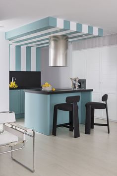 a modern kitchen with blue and white stripes on the walls, counter tops and stools