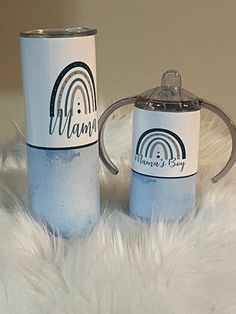 two coffee mugs sitting on top of a white fur covered floor next to each other