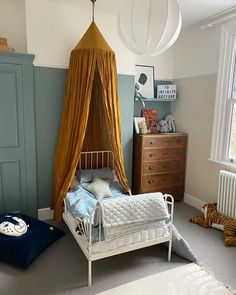 a child's bedroom with a canopy bed and tiger pillows on the floor next to it