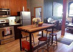 a kitchen table with stools in front of an oven and refrigerator freezer next to a stove