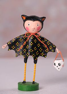 a little doll with a cat costume holding a ball and a skull on it's back