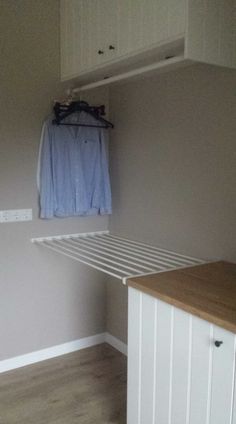 an empty laundry room with clothes hanging on the rack and wooden flooring next to it