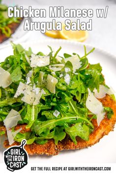 a white plate topped with chicken and arugula salad on top of lettuce