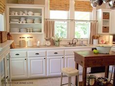 a kitchen filled with lots of white cupboards and counter top next to a window