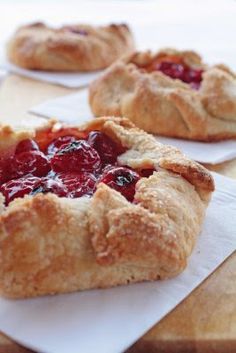 three small pies sitting on top of white napkins next to eachother