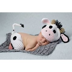 a baby wearing a cow hat laying on top of a blanket