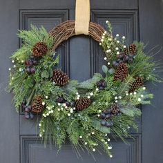 a wreath with pine cones and berries hanging on a door