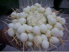 a bowl filled with skewered food on top of a wooden stick table next to a tile floor