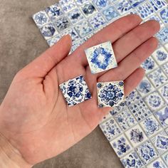 a hand holding three pieces of blue and white tile