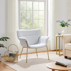 a white chair sitting in front of a window next to a table with a potted plant