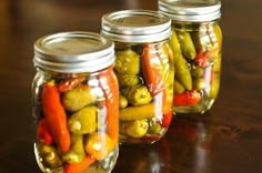 three jars filled with pickles and peppers