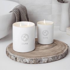 two white candles sitting on top of a wooden tray