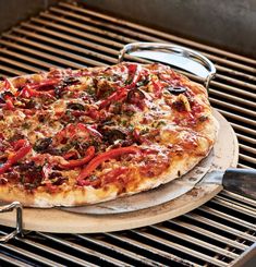 a pizza sitting on top of a grill next to a spatula