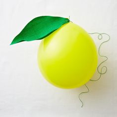 a balloon with a green leaf attached to it's side on a white surface