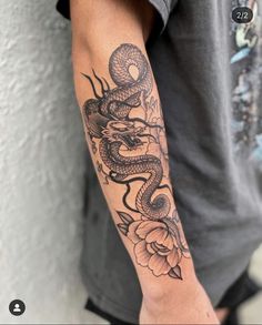 a man with a tattoo on his arm holding a flower and a snake in it