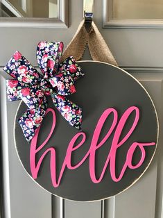 a door hanger with the word hello painted on it and a pink bow tied to it