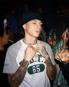 a young man with tattoos on his arms and chest standing in front of a crowd