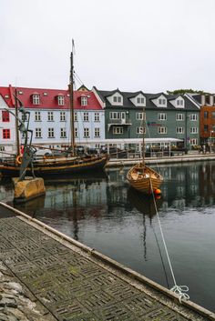 two boats are docked in the water next to some buildings and cobblestone walkways