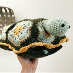 a hand holding a crocheted turtle pillow in the shape of a fish on it's back