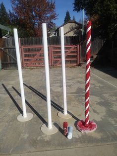 three red and white poles standing in the middle of a cement area next to a fence