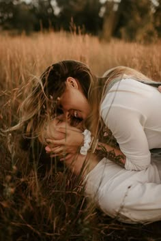 a woman kneeling down in the grass with her hands on her face and eyes closed