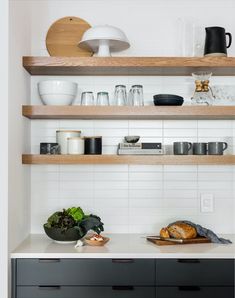 a kitchen with open shelving and wooden shelves