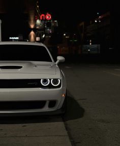 a white car is parked on the side of the road in the dark at night