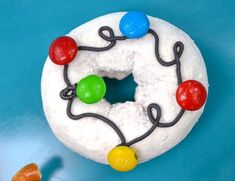 a doughnut with icing and colored candies on the top, sitting on a blue surface