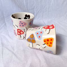 two ceramic cups with designs on them sitting next to each other in front of a white background