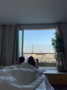 Couple laying in bed looking at the balcony where you can see the eiffel tower. Honeymoon In Paris Aesthetic, Paris Aesthetic Honeymoon, Caring Man Aesthetic, Couples Paris Aesthetic, Couple In A Bedroom Aesthetic, Hotel Aesthetic Couple, France Couple Aesthetic, Europe Honeymoon Aesthetic, Living In Paris Life