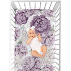 a baby laying in a crib with purple flowers on it