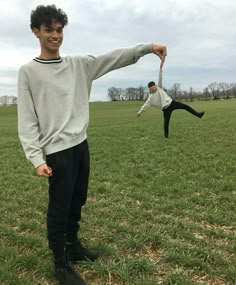 two young men are playing frisbee in a field