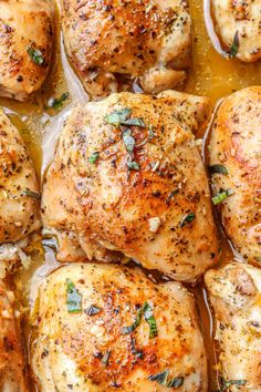 closeup of chicken thighs in a pan with gravy and herbs on top