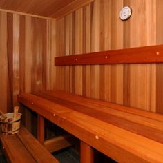 the inside of a wooden sauna with benches and a clock mounted on the wall