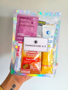 a person holding up a bag with various items inside it, including handover kit and vitamins