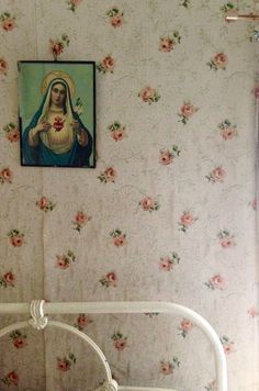 a small white bed sitting in a bedroom next to a wall with flowers on it