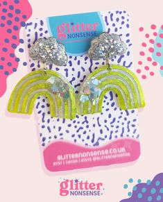 the glitter rainbow earrings are on display in front of a pink and blue polka dot background