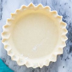 an uncooked pie crust sitting on top of a marble countertop next to a blue towel