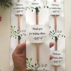 a person holding up several thank you note cards and wooden matchessticks with writing on them